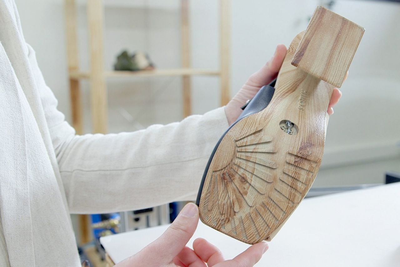 a woman holds a 3D printed shoe, showing the sole